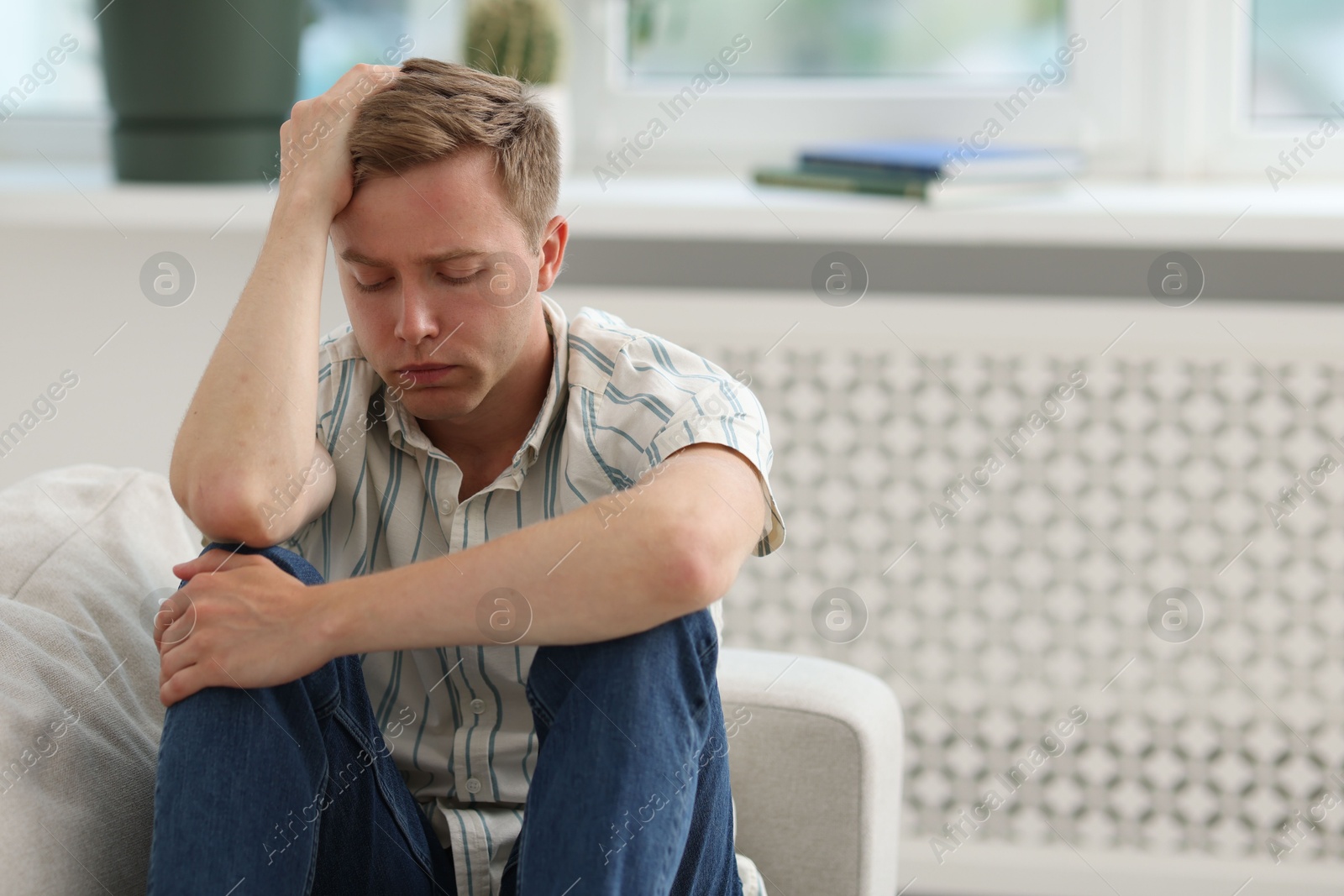 Sad thoughtful man sitting on sofa at home, space for text Photo of Sad thoughtful man sitting on sofa at home, space for text