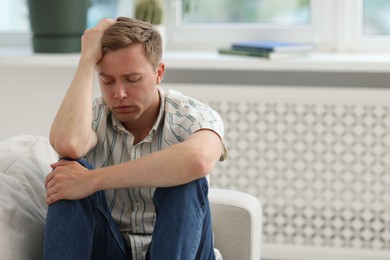 Photo of Sad thoughtful man sitting on sofa at home, space for text