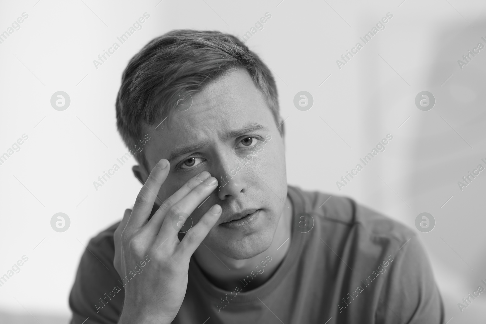 Sad man crying on blurred grey background, black and white effect Photo of Sad man crying on blurred grey background, black and white effect