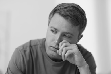 Photo of Sad man crying on blurred grey background, black and white effect