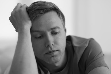 Photo of Sad man on blurred grey background, black and white effect