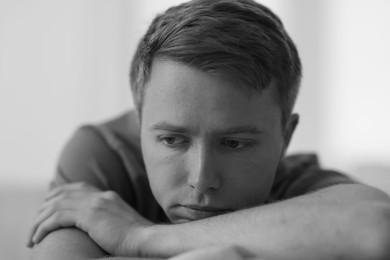 Photo of Sad thoughtful man on blurred grey background, black and white effect
