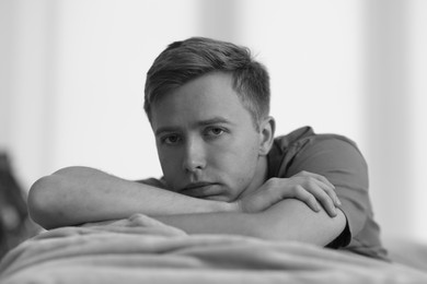 Photo of Sad thoughtful man on blurred grey background, black and white effect