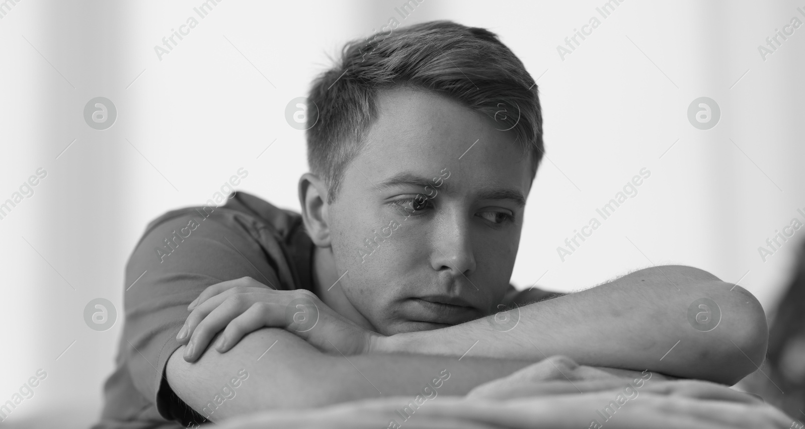 Sad thoughtful man on blurred grey background, black and white effect Photo of Sad thoughtful man on blurred grey background, black and white effect