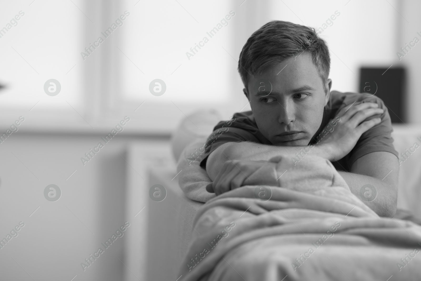 Sad thoughtful man on sofa at home, space for text. Black and white effect Photo of Sad thoughtful man on sofa at home, space for text. Black and white effect