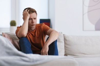 Photo of Sad thoughtful man on sofa at home