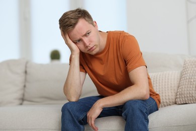 Photo of Sad thoughtful man on sofa at home