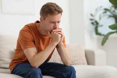 Photo of Sad thoughtful man on sofa at home