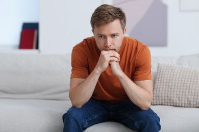 Photo of Sad thoughtful man on sofa at home