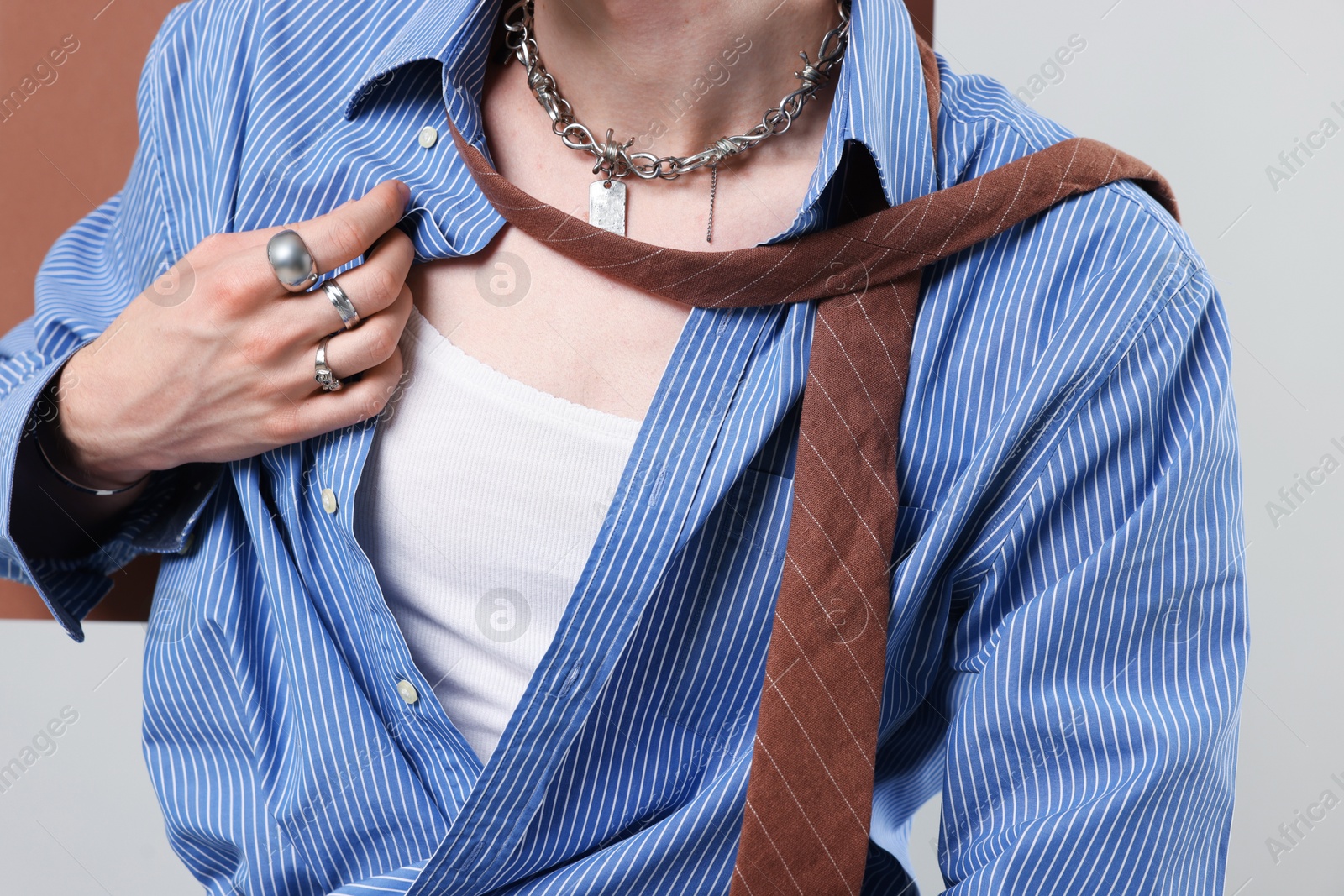 Photo of Young man wearing stylish clothes, rings and chain on light grey background, closeup