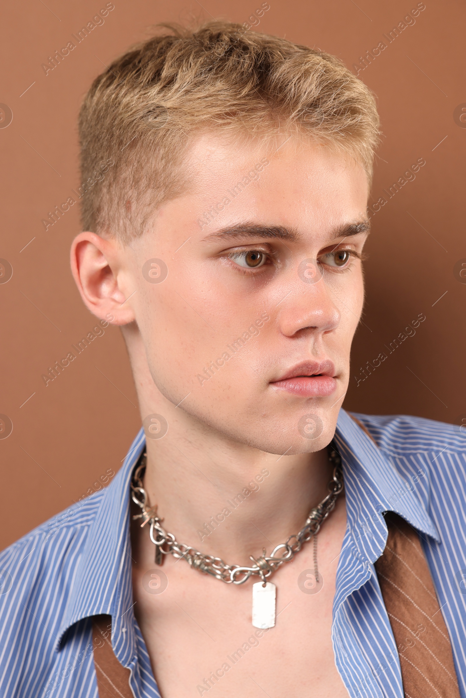 Photo of Handsome young man wearing stylish clothes and chain on light brown background