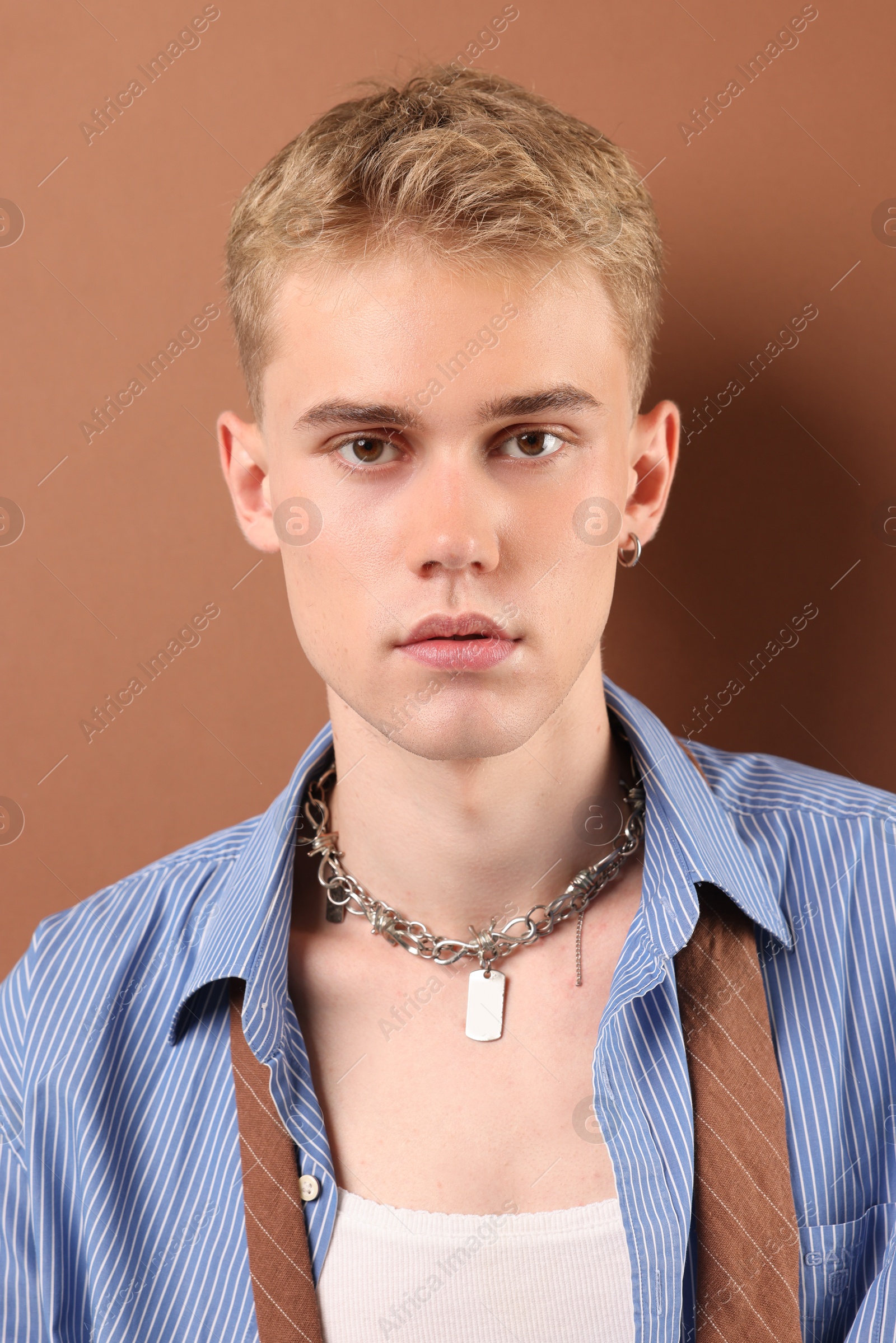 Photo of Handsome young man wearing stylish clothes and chain on light brown background