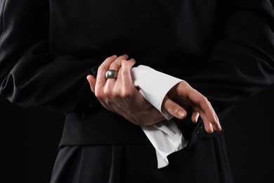 Photo of Young man wearing stylish suit and ring on black background, closeup