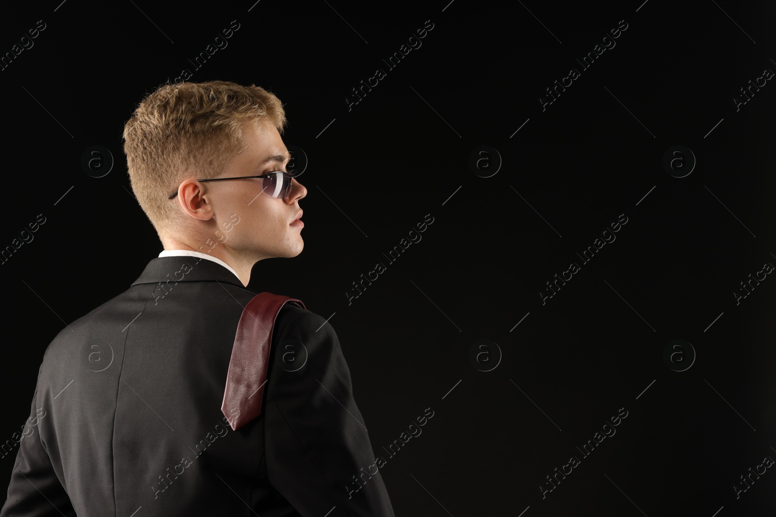 Photo of Handsome young man wearing stylish suit and sunglasses on black background, space for text