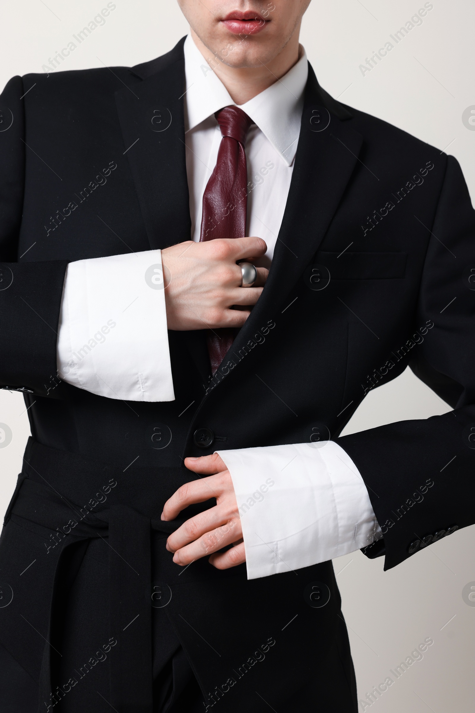Photo of Young man wearing stylish suit and ring on white background, closeup