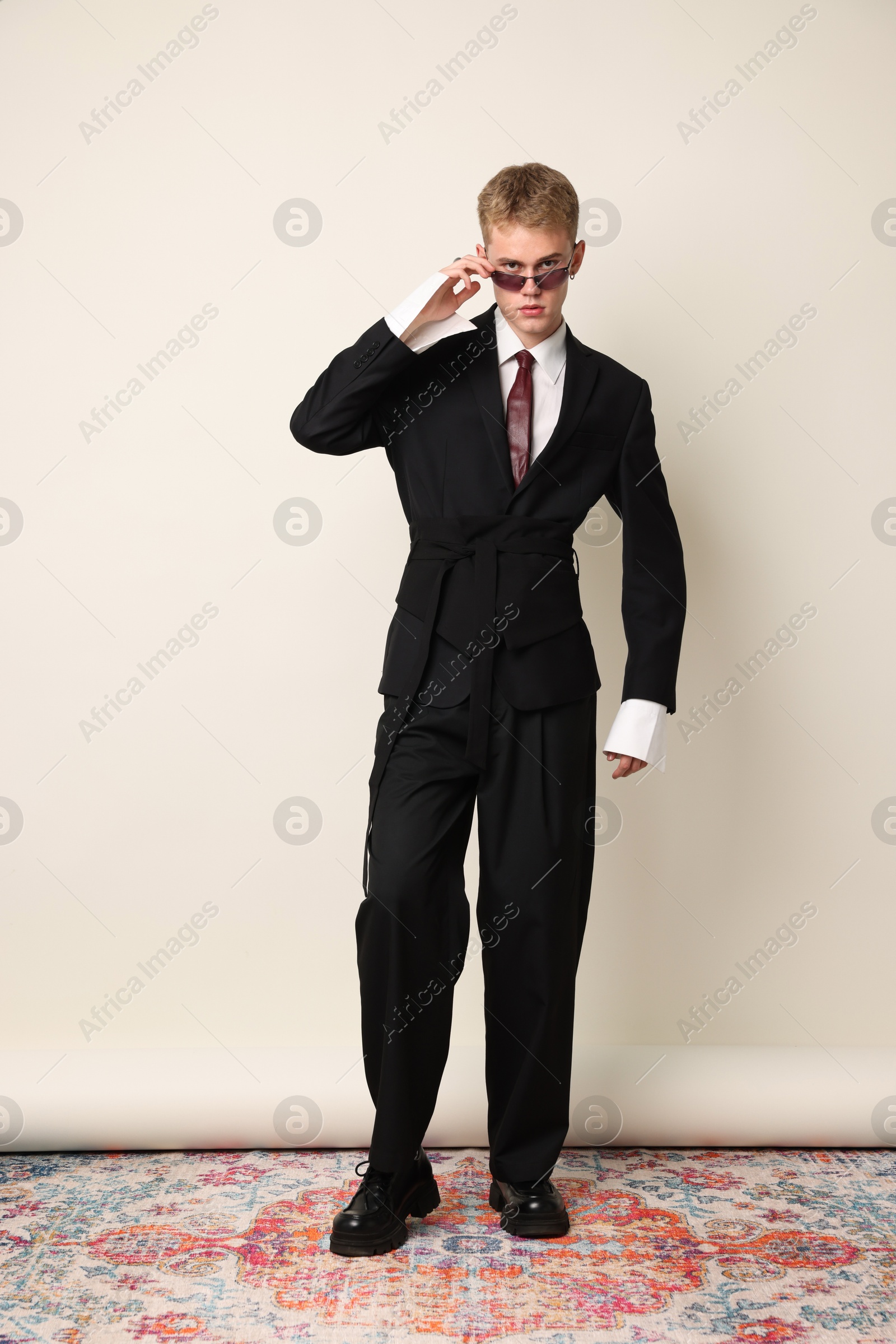Photo of Handsome young man wearing stylish suit and sunglasses on white background