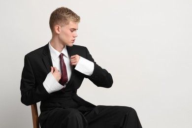 Photo of Handsome young man wearing stylish suit sitting on chair against white background, space for text
