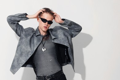 Photo of Handsome young man wearing jacket and sunglasses on white background, space for text