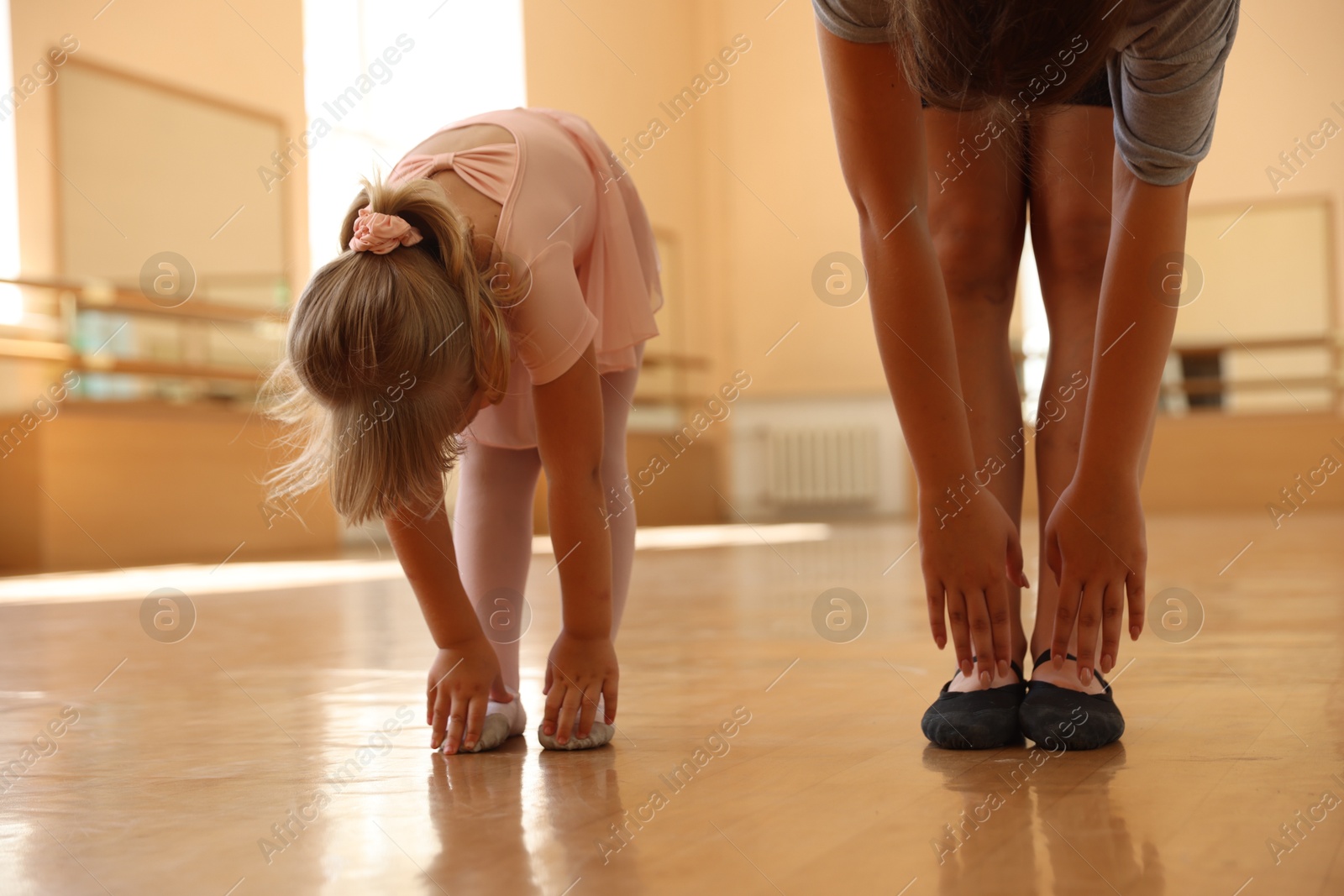 Ballet teacher stretching with little girl in dance class, closeup Photo of Ballet teacher stretching with little girl in dance class, closeup