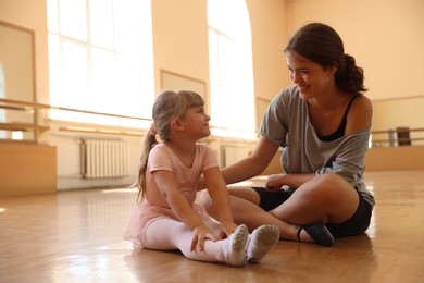 Photo of Happy ballet teacher working with little girl on floor in dance class