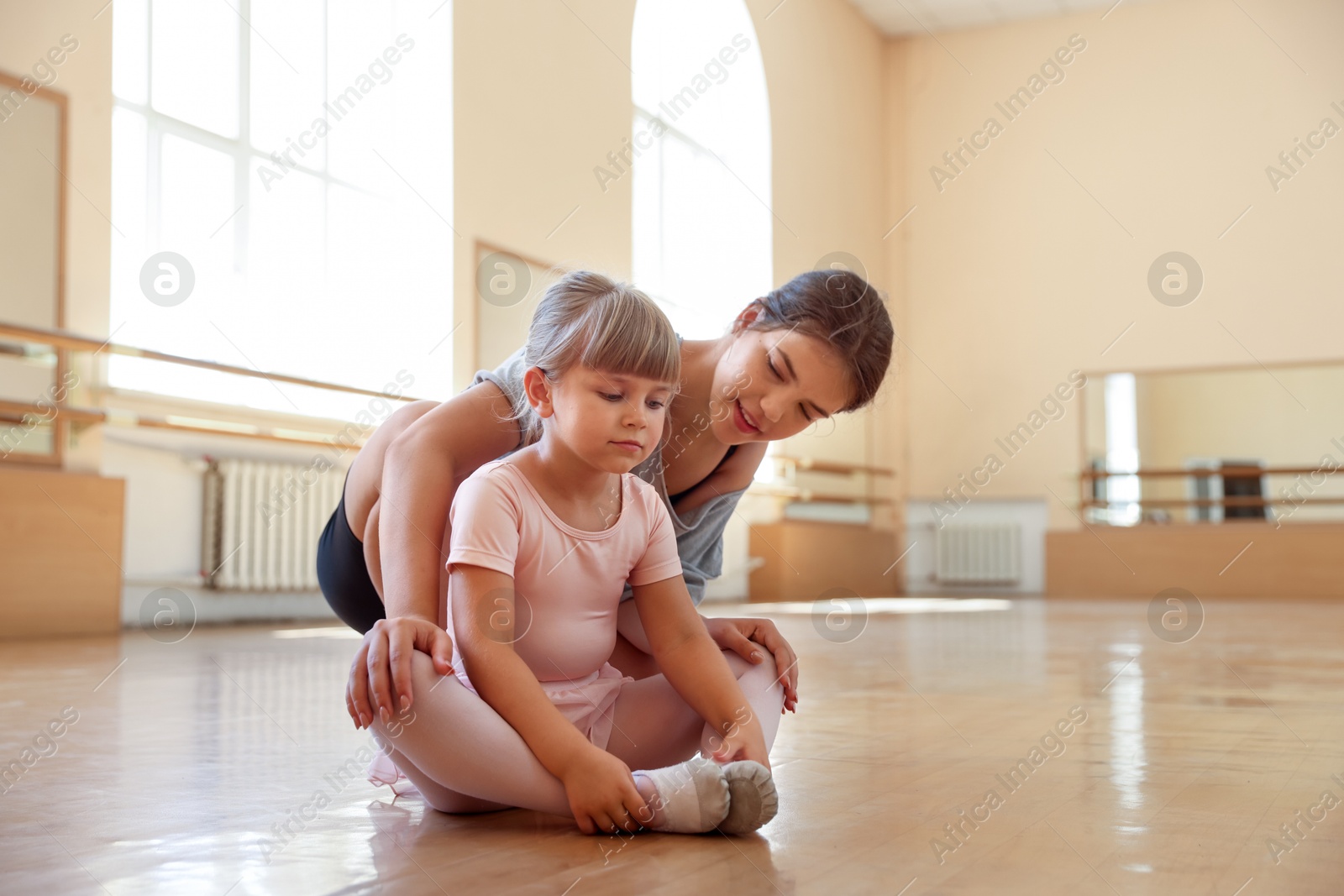 Ballet teacher working with little girl on floor in dance class Photo of Ballet teacher working with little girl on floor in dance class