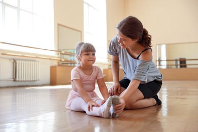 Photo of Happy ballet teacher working with little girl on floor in dance class