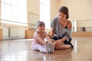 Photo of Ballet teacher working with little girl on floor in dance class