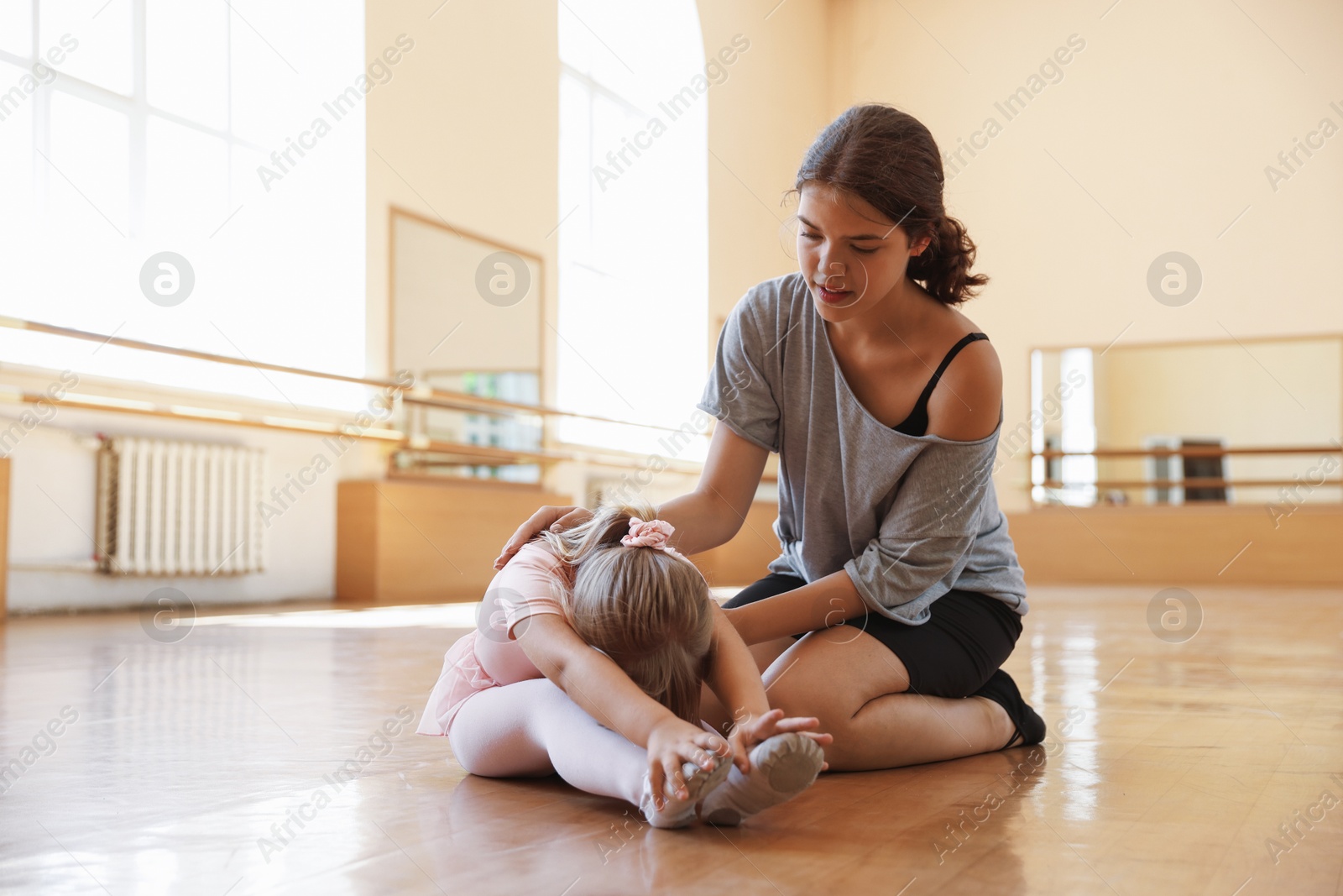 Ballet teacher helping little girl to stretch in dance class Photo of Ballet teacher helping little girl to stretch in dance class