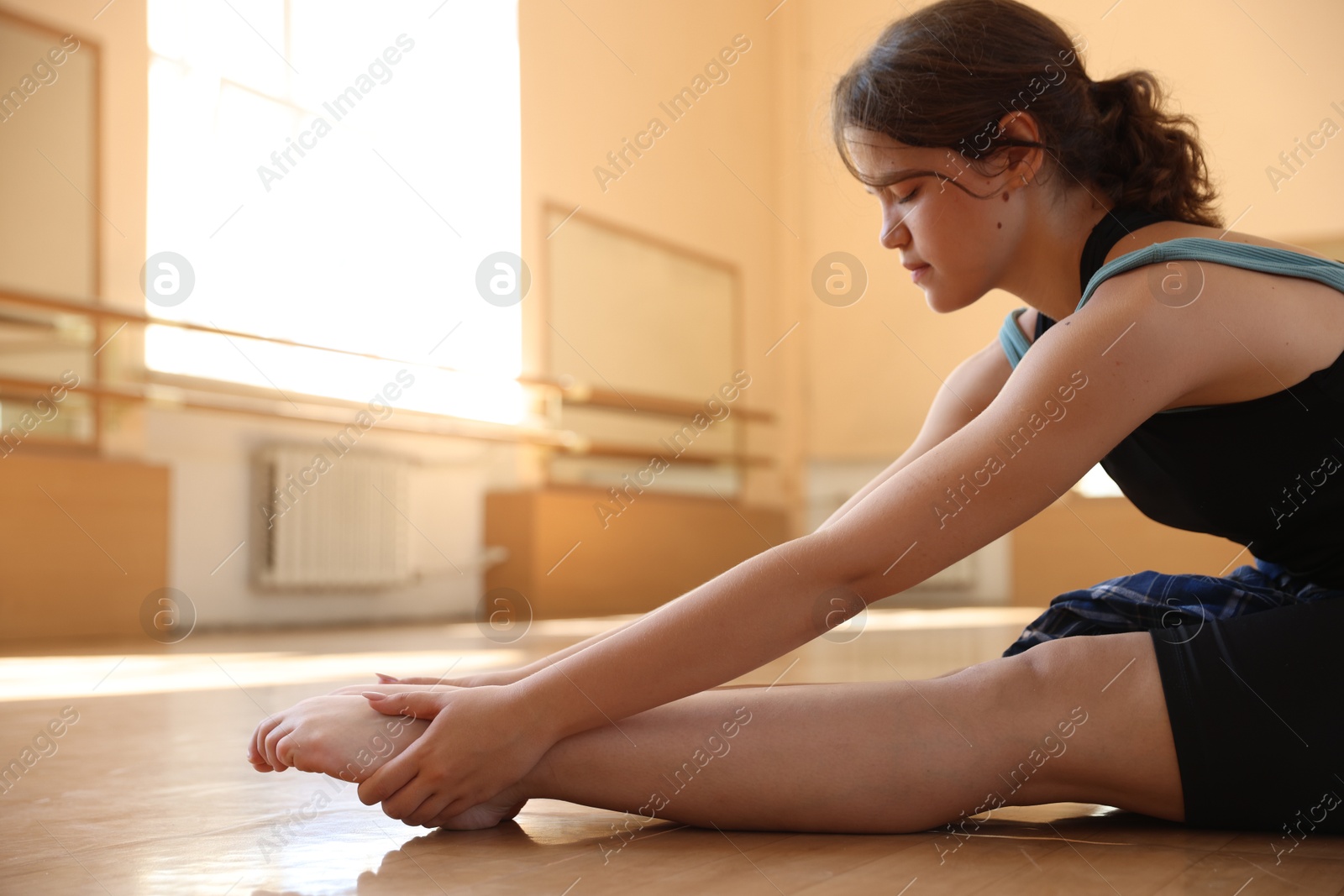 Teenage girl stretching on floor in dance class Photo of Teenage girl stretching on floor in dance class