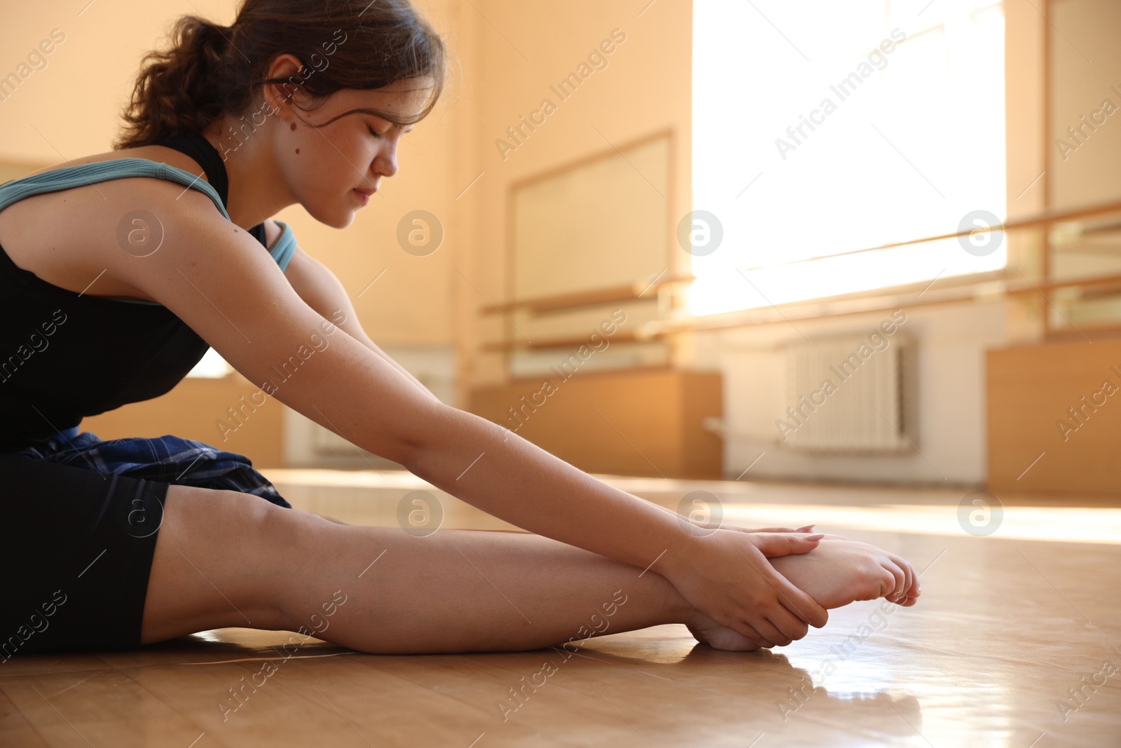 Teenage girl stretching on floor in dance class Photo of Teenage girl stretching on floor in dance class