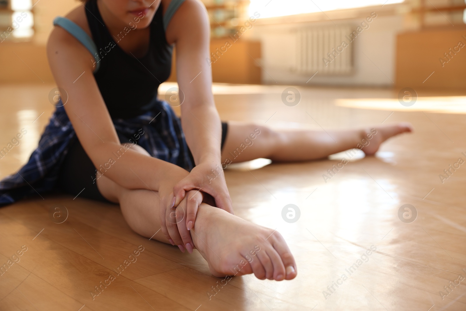 Teenage girl stretching on floor in dance class, closeup Photo of Teenage girl stretching on floor in dance class, closeup
