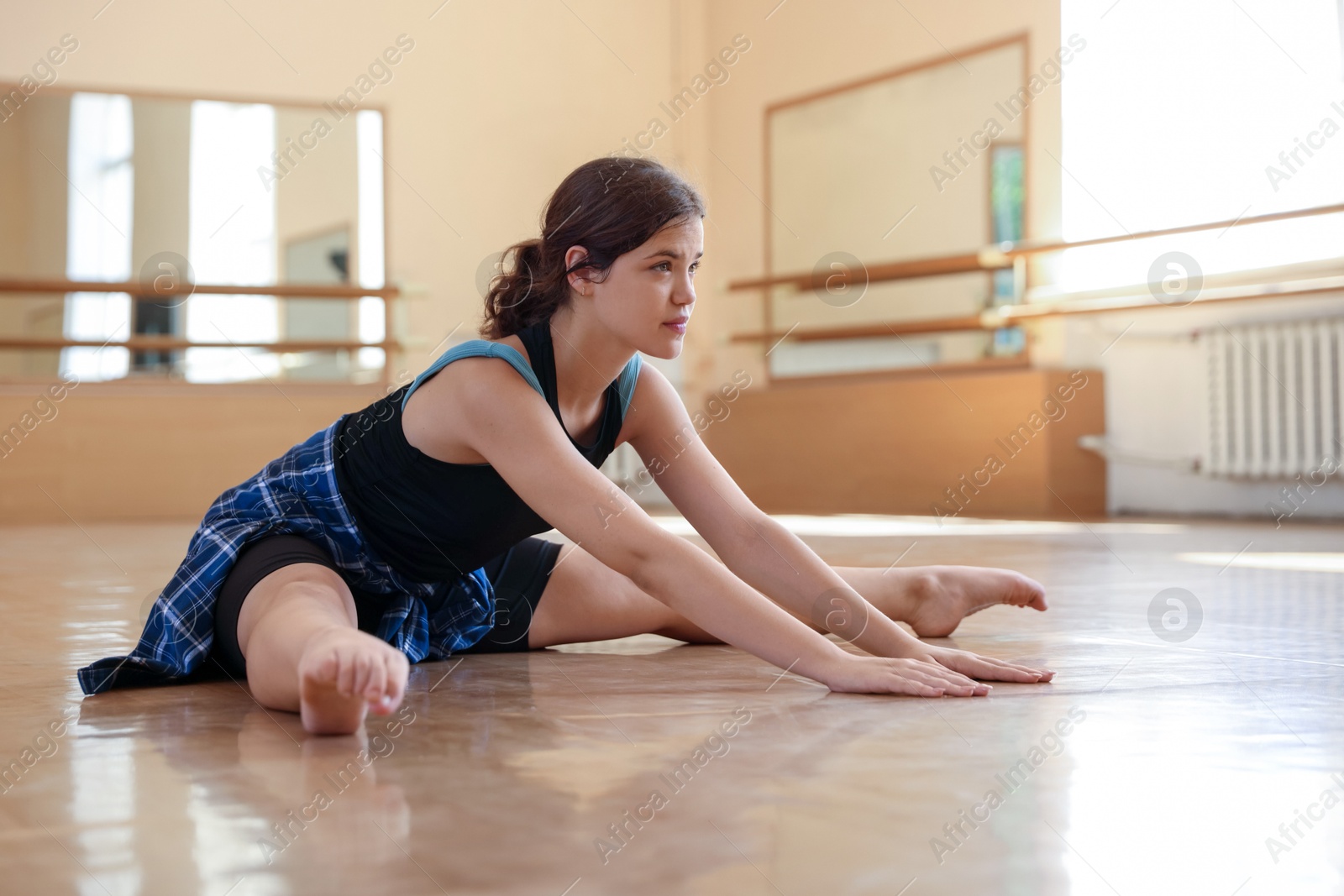 Photo of Teenage girl stretching on floor in barre studio