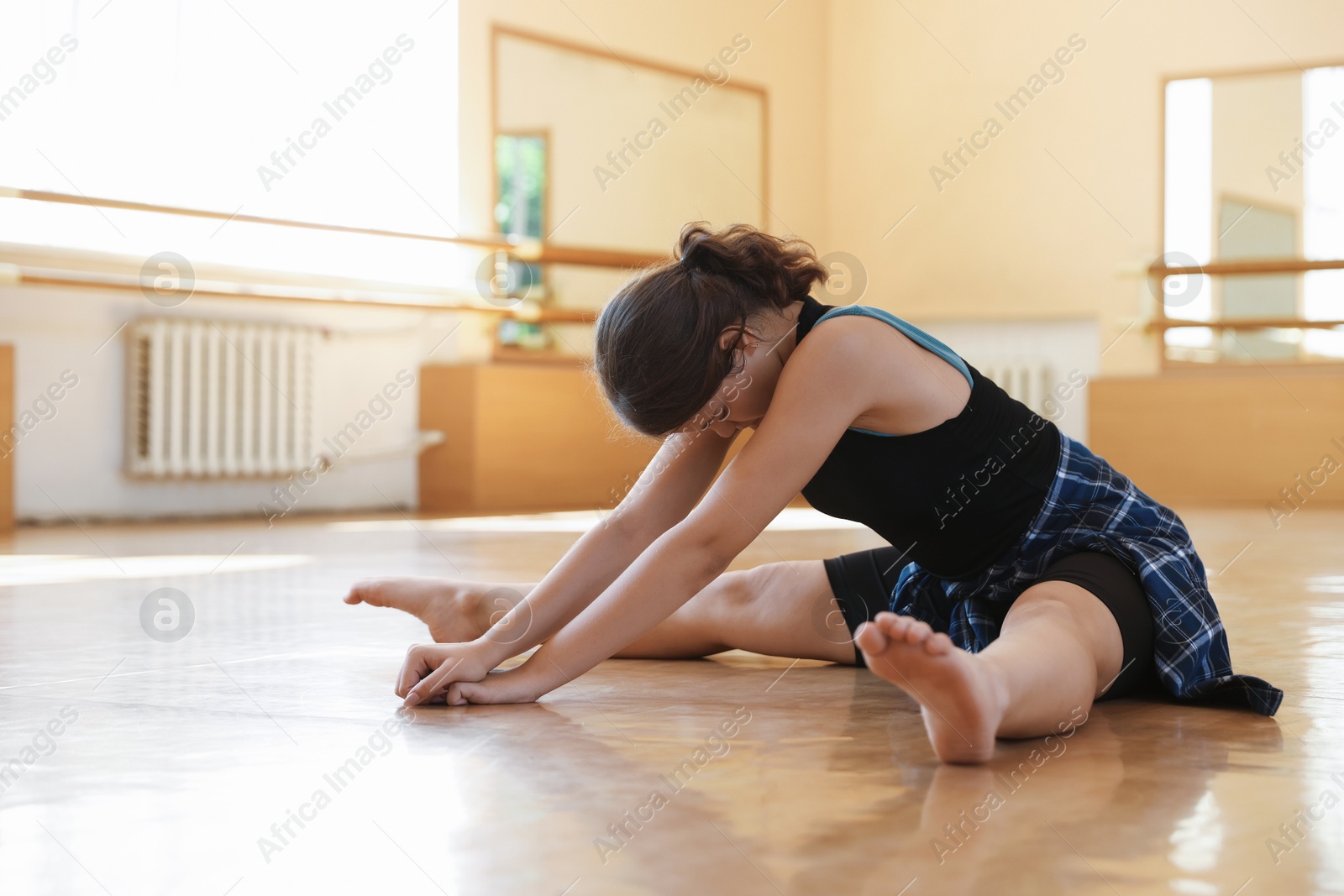 Photo of Teenage girl stretching on floor in barre studio