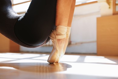 Photo of Teenage girl in pointe shoes training indoors, closeup