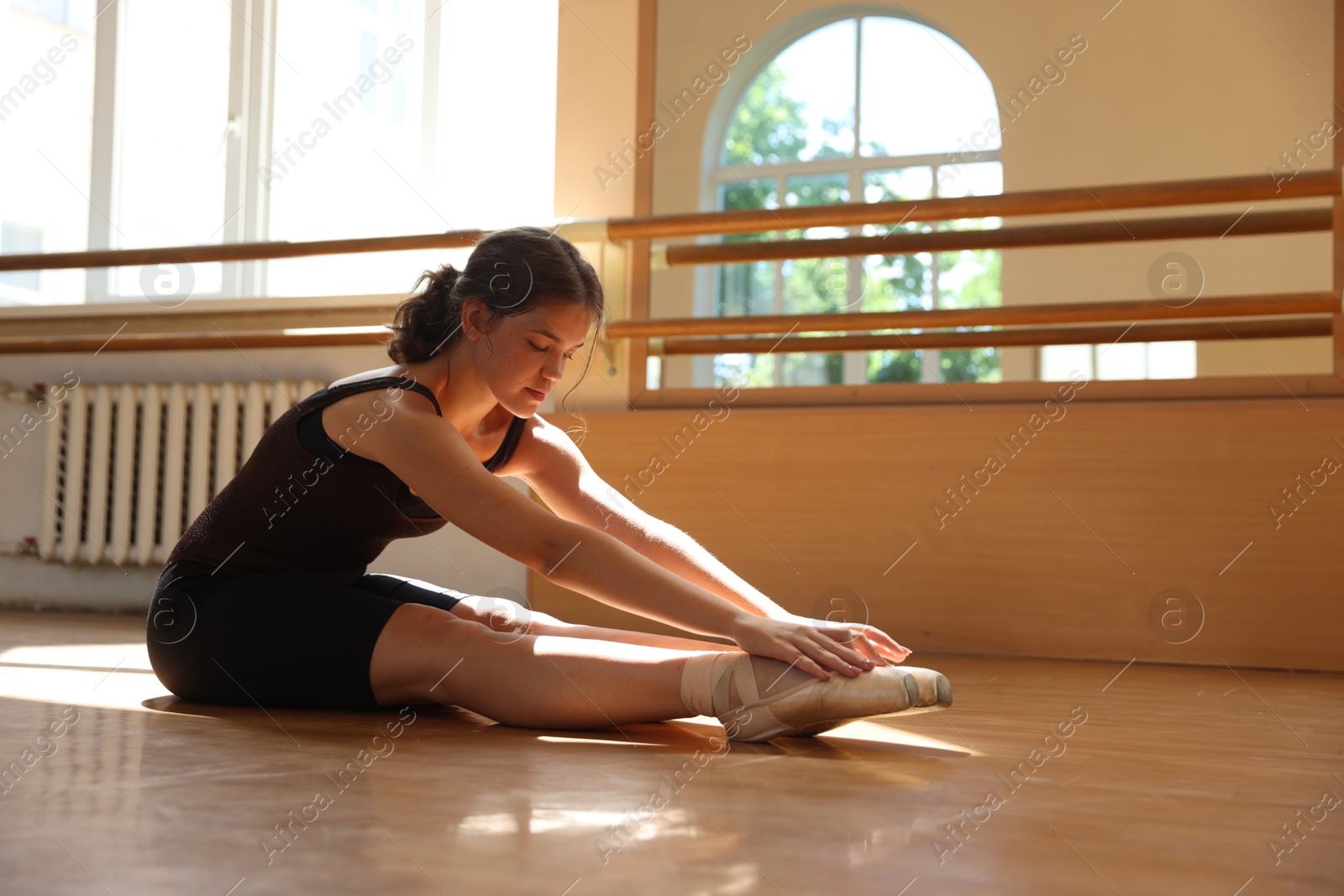 Beautiful teenage girl stretching on floor in light barre studio Photo of Beautiful teenage girl stretching on floor in light barre studio