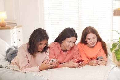 Photo of Friends with smartphones on bed at home