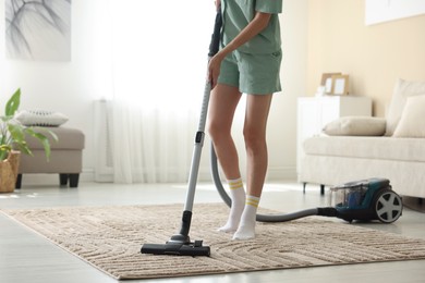 Photo of Woman cleaning carpet with vacuum cleaner at home, closeup