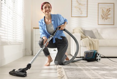 Photo of Woman cleaning floor with vacuum cleaner at home