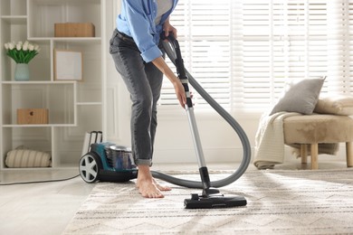 Photo of Woman cleaning carpet with vacuum cleaner at home, closeup