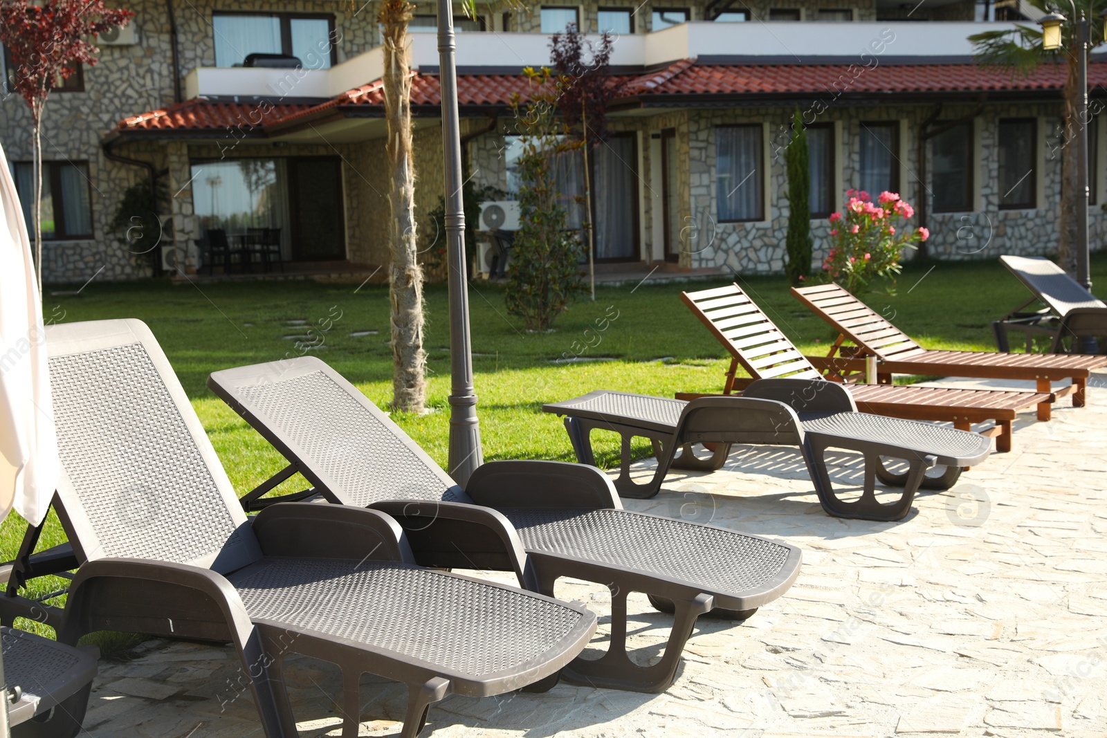 Photo of Many sunbeds near building outdoors on sunny day