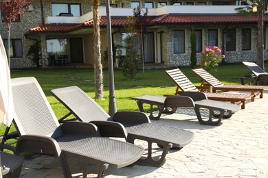 Photo of Many sunbeds near building outdoors on sunny day