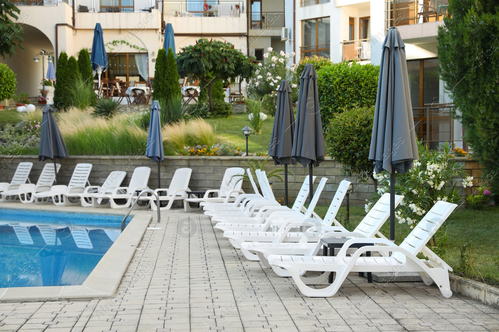 Photo of Sunbeds, umbrellas and outdoor swimming pool near hotel at luxury resort