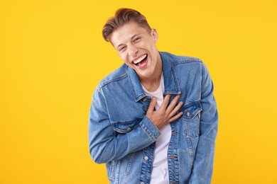 Photo of Handsome man laughing on yellow background. Positive emotion