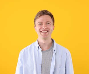 Photo of Handsome man laughing on yellow background. Positive emotion