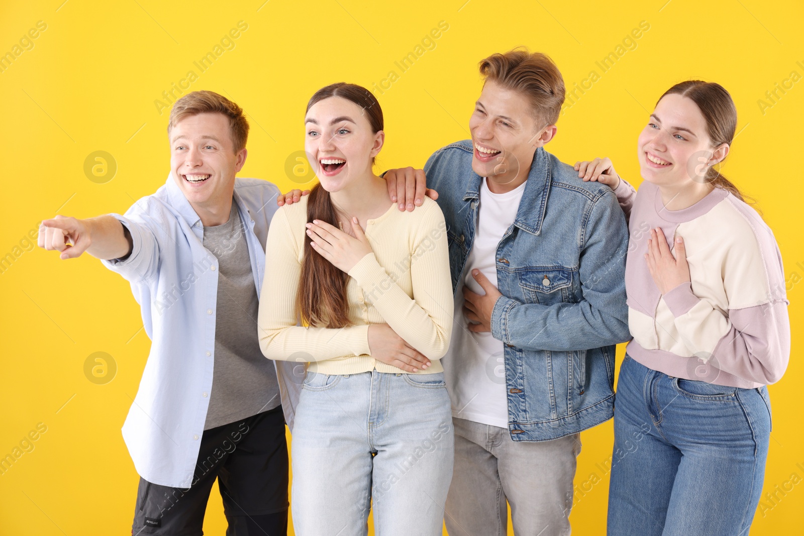 Friends laughing and looking at something on yellow background. Positive emotion Photo of Friends laughing and looking at something on yellow background. Positive emotion