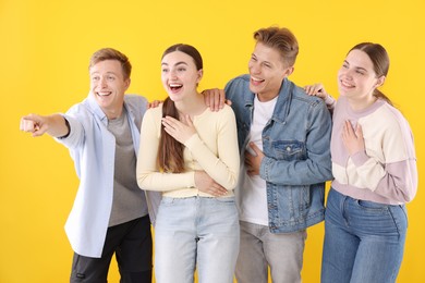 Photo of Friends laughing and looking at something on yellow background. Positive emotion