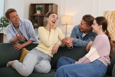 Photo of Friends laughing on sofa indoors. Positive emotion