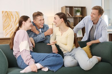 Photo of Friends laughing on sofa indoors. Positive emotion
