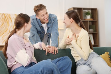 Photo of Friends laughing on sofa indoors. Positive emotion