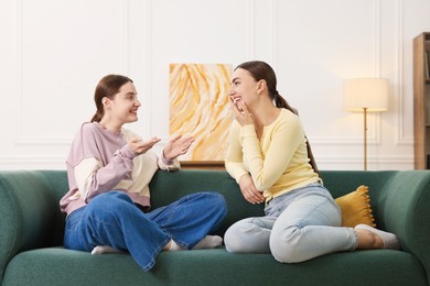 Photo of Friends laughing on sofa indoors. Positive emotion